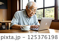 カフェでノートパソコンを操作するシニア男性（自然光とコーヒーカップ） 125376198