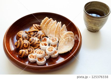 木のお皿に入ったかりんとう、生姜煎餅などの和菓子(お茶菓子) と日本茶 木のお皿に入ったかりんとう、生姜煎餅などの和菓子(お茶菓子) と日本茶 125376338
