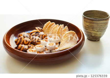 木のお皿に入ったかりんとう、生姜煎餅などの和菓子(お茶菓子) と日本茶	 125376339