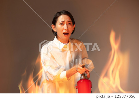 女性　火災　消火器 125377056