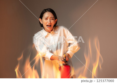 女性　火災　消火器 125377060