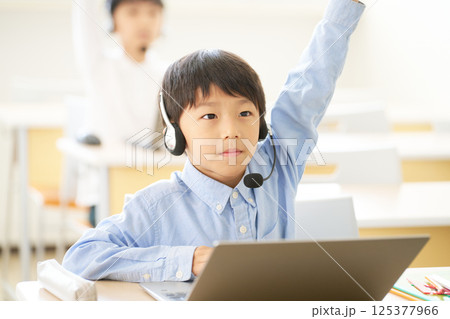 ノートパソコンを開いて手を挙げる小学生の男の子 ノートパソコンを開いて手を挙げる小学生の男の子 125377966