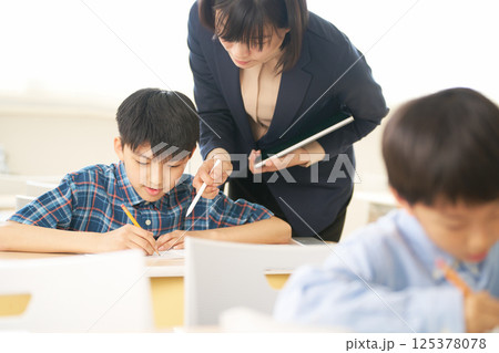先生に教わりながら学ぶ小学生の男の子｜対話を大切にする教育の現場 125378078