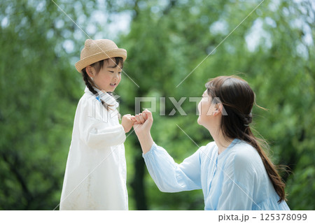 新緑の背景で指切りの約束をする子どもと大人　未来や希望、約束を叶える守るなどのイメージ 125378099