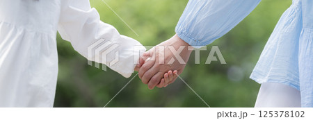新緑背景で親子で手を繋ぐ愛情などのイメージ 顔無し手元のクローズアップ 新緑背景で親子で手を繋ぐ愛情などのイメージ 顔無し手元のクローズアップ 125378102