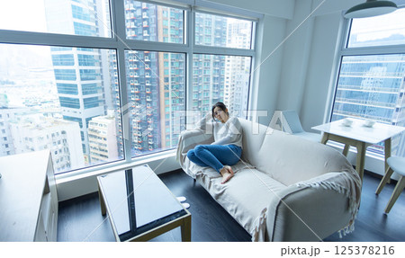 woman wear glasses sit on the sofa and feel stressed, full body shot with house estate background woman wear glasses sit on the sofa and feel stressed, full body shot with house estate background 125378216
