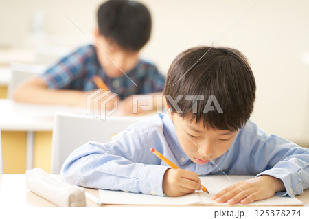 一心に書き込む小学生の男の子｜勉強に没頭する真剣な表情 125378274