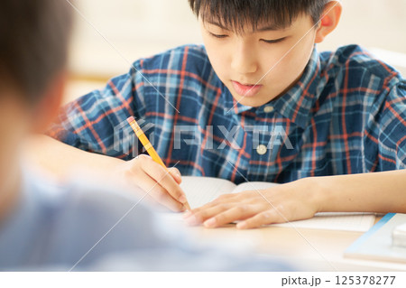 一心に書き込む小学生の男の子|勉強に没頭する真剣な表情 一心に書き込む小学生の男の子|勉強に没頭する真剣な表情 125378277