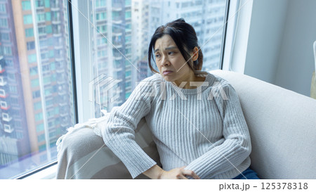 woman wear glasses sit on the sofa and feel stressed, full body shot with house estate background 125378318