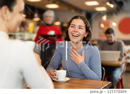 Girl in cafe sits opposite female companion, has nice conversation 125378804