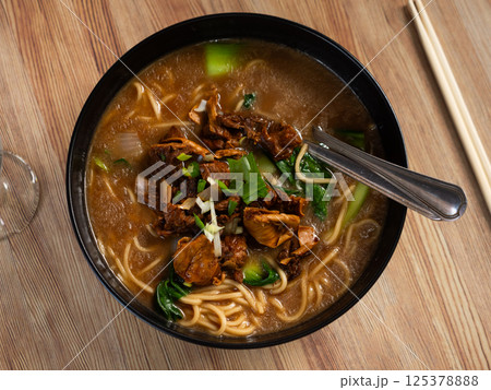 Beef soup with noodles and vegetables on a wooden background 125378888