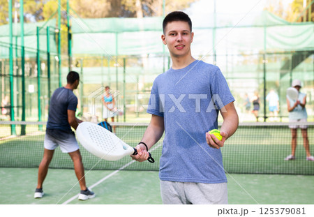 Portrait of positive boy on padel tennis court Portrait of positive boy on padel tennis court 125379081