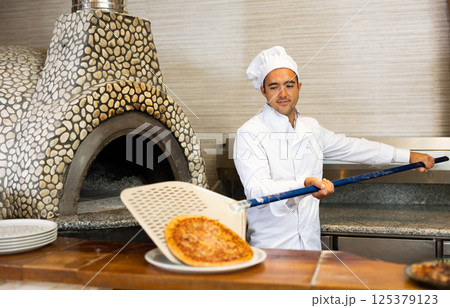 Skilled man chef preparing pizza in restaurant 125379123