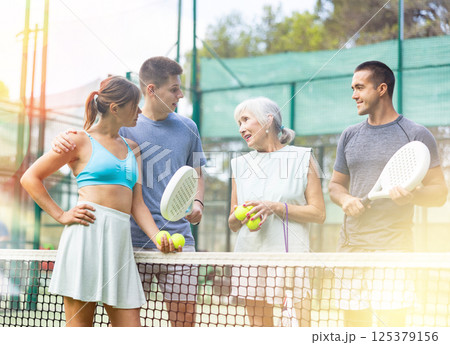 Two pairs of padel players are happily discussing past game on an open court 125379156