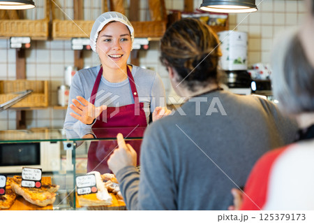 Saleswoman offers bakery customers to buy fresh baked goods Saleswoman offers bakery customers to buy fresh baked goods 125379173