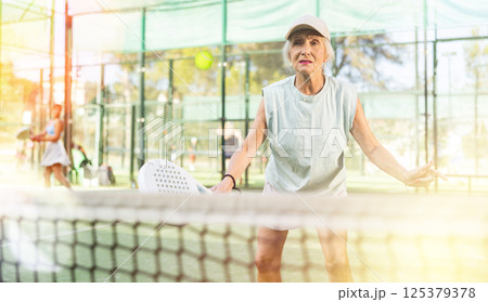 Mature woman playing padel tennis on court 125379378