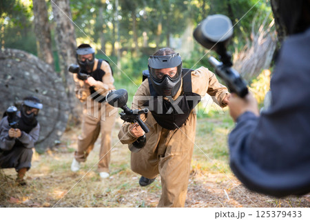 Team of paintball players attacks enemy at an army training ground Team of paintball players attacks enemy at an army training ground 125379433