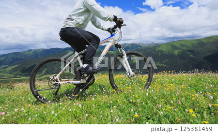 Riding mountain bike on flowering grassland mountain top 125381459