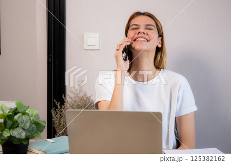 Young caucasian businesswoman talking with smartphone and working on laptop computer. Young caucasian businesswoman talking with smartphone and working on laptop computer. 125382162