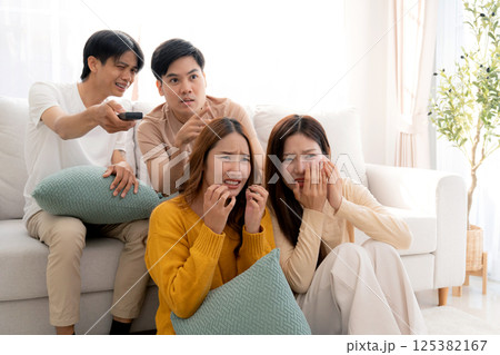 Group asian friends watching a horror movie at home with reaction with fear and surprise. Group asian friends watching a horror movie at home with reaction with fear and surprise. 125382167
