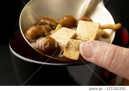 赤味噌を使ったなめこと豆腐の味噌汁をお椀に盛り付ける 125382292