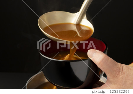 赤味噌を使ったなめこと豆腐の味噌汁をお椀に盛り付ける 赤味噌を使ったなめこと豆腐の味噌汁をお椀に盛り付ける 125382295