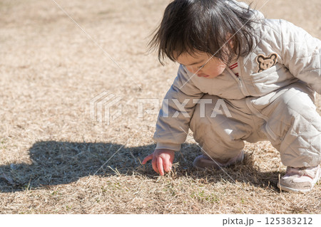 【相模原市立麻溝公園の芝生広場で遊ぶ1歳児　しゃがむ】 125383212