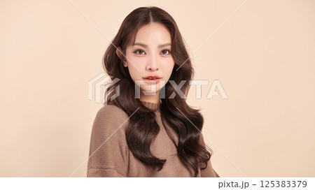 A beautiful young Asian woman with clean, fresh skin against a beige background. Skincare, facial treatment, cosmetology, beauty, and spa. An elegant portrait of an Asian woman. A beautiful young Asian woman with clean, fresh skin against a beige background. Skincare, facial treatment, cosmetology, beauty, and spa. An elegant portrait of an Asian woman. 125383379