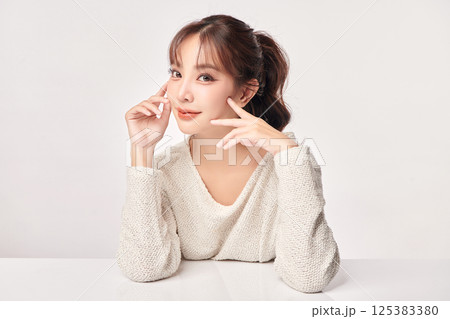 A beautiful young Asian woman with clean, fresh skin against a white background. Skincare, facial treatment, cosmetology, beauty, and spa. An elegant portrait of an Asian woman. 125383380