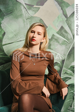 Young woman poses confidently in a stylish setting with tropical backdrop 125386694
