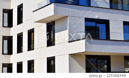 Modern architecture of urban residential apartment buildings on a sunny day. Low-rise apartment buildings with large windows and extensive terraces. White facade of a modern apartment building. Modern architecture of urban residential apartment buildings on a sunny day. Low-rise apartment buildings with large windows and extensive terraces. White facade of a modern apartment building. 125388349