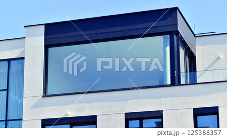 Modern architecture of urban residential apartment buildings on a sunny day. Low-rise apartment buildings with large windows and extensive terraces. White facade of a modern apartment building. 125388357