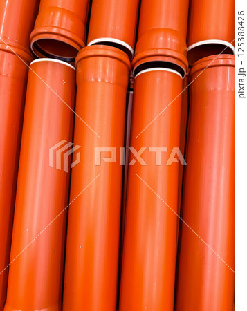 Stack of orange plastic drainage or plumbing pipes displayed in hardware store. High quality photo Stack of orange plastic drainage or plumbing pipes displayed in hardware store. High quality photo 125388426