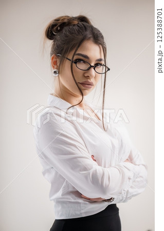 Portrait of a young woman in a white shirt and black pants, looking confidently at the camera 125388701