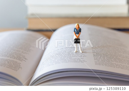 机の上に開いた英語の書籍と女性のフィギア 研究 学習 学び直しのイメージ 机の上に開いた英語の書籍と女性のフィギア 研究 学習 学び直しのイメージ 125389110