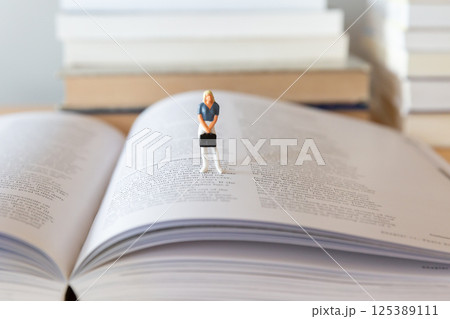 机の上に開いた英語の書籍と女性のフィギア  研究 学習 学び直しのイメージ  125389111