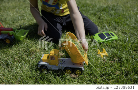 A child plays with toy cars on the lawn in the sunny day 125389631