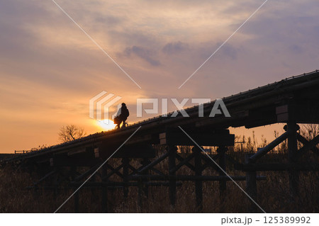 [流れ橋]夕暮れ時の美しい橋を渡る人々 125389992