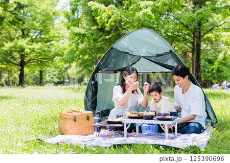 キャンプで料理を楽しむ仲良し家族・アウトドアイメージ 125390696