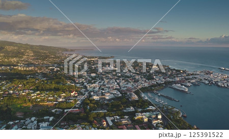 Aerial view of Papeete, the capital city of French Polynesia, showcasing its harbor, cityscape, lush greenery, and the vast pacific ocean during the golden hour Aerial view of Papeete, the capital city of French Polynesia, showcasing its harbor, cityscape, lush greenery, and the vast pacific ocean during the golden hour 125391522