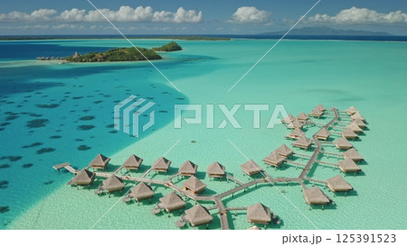 Luxury overwater bungalows resort invite for relaxation and escape. Crystal clear turquoise water, tropical island paradise. Exotic travel vacation getaway, romantic honeymoon. Aerial drone panorama. Luxury overwater bungalows resort invite for relaxation and escape. Crystal clear turquoise water, tropical island paradise. Exotic travel vacation getaway, romantic honeymoon. Aerial drone panorama. 125391523