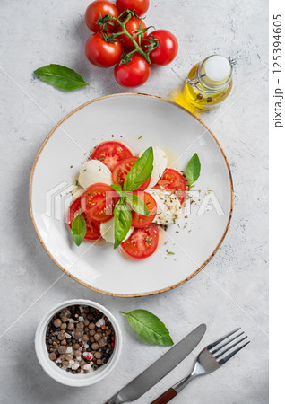 Flat lay of caprese salad with sliced tomatoes, mozzarella and basil  on a light background 125394605