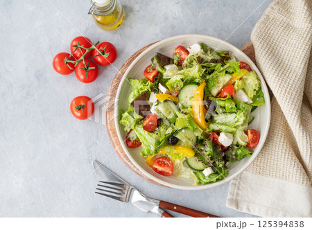 Fresh vegetable salad with feta cheese and olives on plate on a light background. Fresh vegetable salad with feta cheese and olives on plate on a light background. 125394838