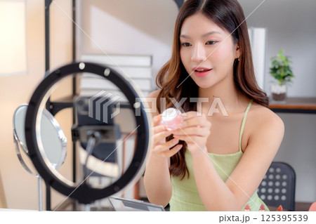 Young asian woman presenting and review cosmetic product with excitement on social media platform. Young asian woman presenting and review cosmetic product with excitement on social media platform. 125395539