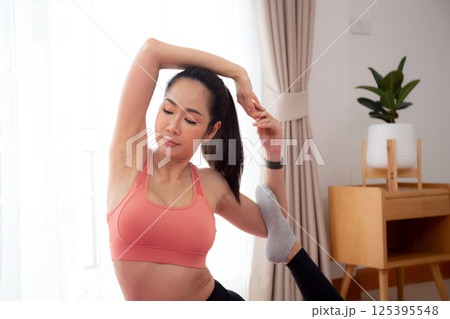 Young asian woman practicing Yoga with stretching muscle back on yoga mat in living room. Young asian woman practicing Yoga with stretching muscle back on yoga mat in living room. 125395548