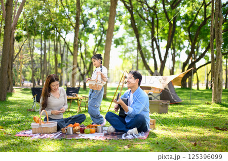 Cheerful family enjoys a picnic near tent at a forest campsite Cheerful family enjoys a picnic near tent at a forest campsite 125396099