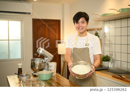 Proud home baker holds a bowl of freshly whipped cream in a kitchen Proud home baker holds a bowl of freshly whipped cream in a kitchen 125396262