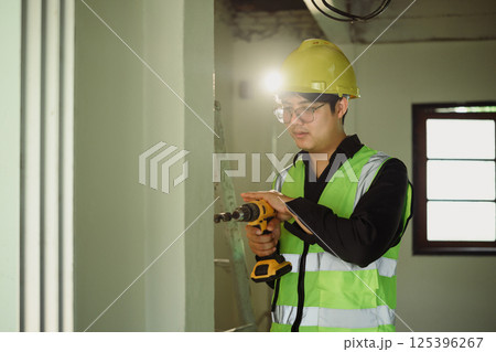Construction worker using electric drill on renovation project 125396267