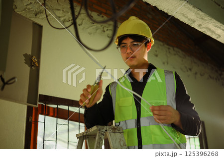 Electrician works on ceiling wiring in renovation site 125396268