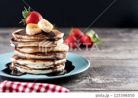 Pancakes with chocolate and fruit on wooden table Pancakes with chocolate and fruit on wooden table 125396850